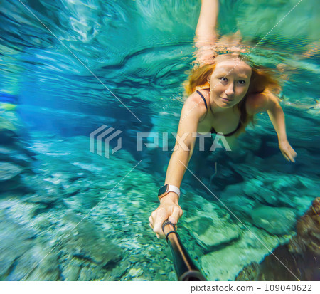 Woman immersed in the enchanting beauty of a Mexican cenote, surrounded by crystal-clear waters and captivating natural formations Woman immersed in the enchanting beauty of a Mexican cenote, surrounded by crystal-clear waters and captivating natural formations 109040622