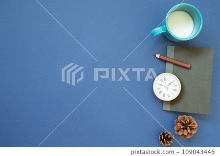 Notebook, clock, colored pencil, cup of milk with pine cone on navy blue background. top view, copy space. workspace Notebook, clock, colored pencil, cup of milk with pine cone on navy blue background. top view, copy space. workspace 109043446
