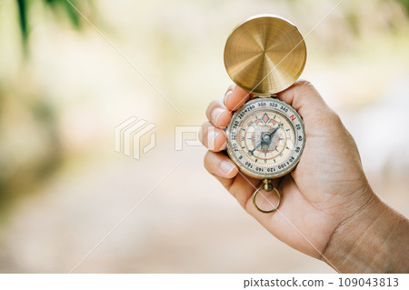 Exploring the forest a woman holds a compass in her hand during a close-up shot. The compass represents guidance and the spirit of exploration. Exploring the forest a woman holds a compass in her hand during a close-up shot. The compass represents guidance and the spirit of exploration. 109043813