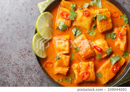 Traditional Sri Lankan Fish Curry made with white fish and filled with asian spices close up on a plate. Horizontal top view 109044091