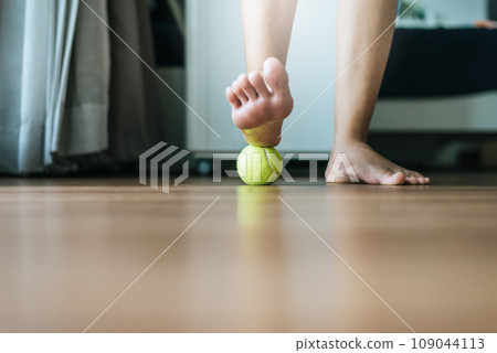 Woman massaging with tennis ball on foot,Feet soles massage for plantar fasciitis Woman massaging with tennis ball on foot,Feet soles massage for plantar fasciitis 109044113