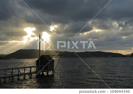 透過雲層的光芒照亮了東鄉湖的四手網，呈現出神秘的景觀。 109044340