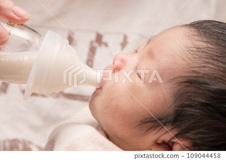 [Newborn baby breastfeeding with a bottle] 109044458