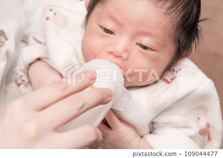[Newborn baby breastfeeding with a bottle] 109044477