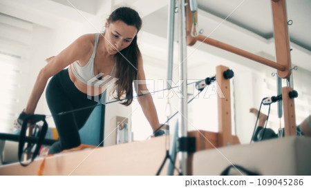 Amateur female practices pilates with ball on the frame reformer in pilates studio 109045286