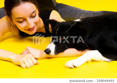 Cute young woman kisses and hugs her puppy border collie dog. Love between owner and dog. Cute young woman kisses and hugs her puppy border collie dog. Love between owner and dog. 109048493