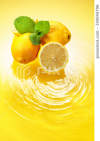 Juicy lemons with mint on a yellow background with water splashes. 109048796