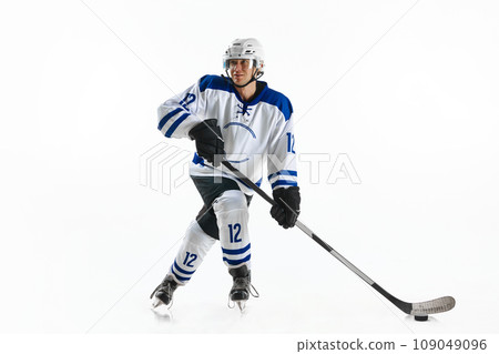 Young man, hockey athlete in motion, standing on rink with stick, training, playing against white studio background 109049096