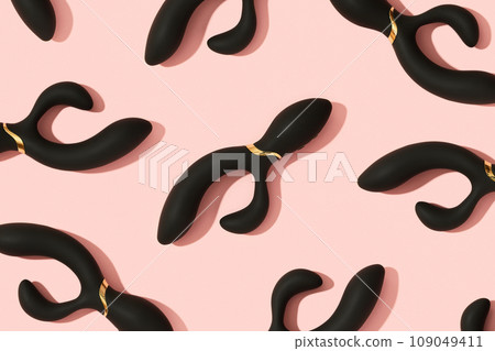 Black vibrator on the peach pink background. Sex toys for adults. Pattern 109049411