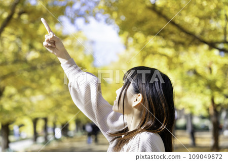 A young woman strolling through a park with autumn leaves A young woman strolling through a park with autumn leaves 109049872