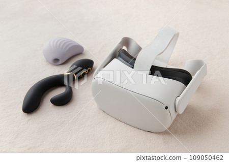 Purple clitoral vibrator, black dildo and virtual reality goggles on the white fur background Purple clitoral vibrator, black dildo and virtual reality goggles on the white fur background 109050462