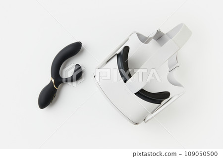 Black vibrator and virtual reality goggles on the white background. Sex toys for adults 109050500
