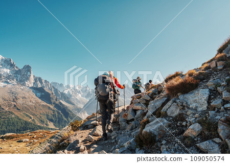 Group of hiker hiking with difficult on mountain trail amidst French alps on sunny day at France Group of hiker hiking with difficult on mountain trail amidst French alps on sunny day at France 109050574