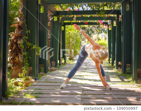 idea of healthy lifestyle and sports in a modern city. Female jogger. Fit young Caucasian woman stretching muscle in park before running and enjoying healthy outdoor. Fitness girl in public park. 109050997