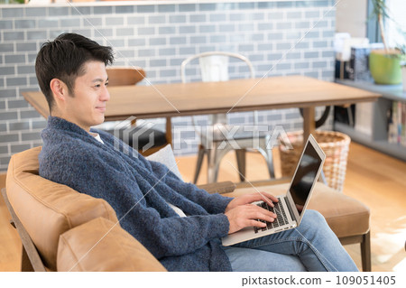 A man looking at a computer in the living room A man looking at a computer in the living room 109051405
