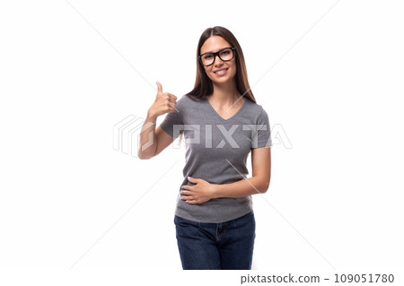 portrait of a caucasian slim young woman in glasses dressed in a gray basic t-shirt and jeans 109051780