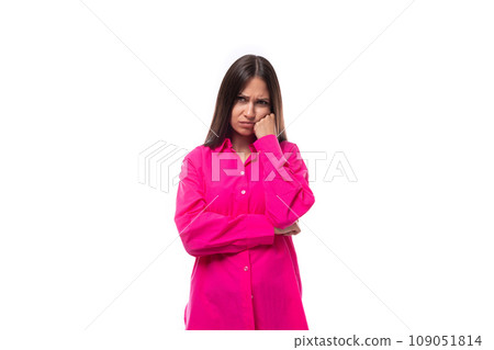 sad young brunette european woman in a crimson shirt on a white background with copy space 109051814