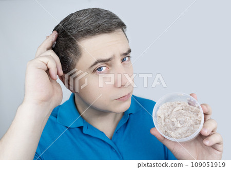 Man does head scrub. Dark-haired young man applies a scalp scrub to combat dandruff, oily scalp, alopecia. Problem skin causing hair problems. Close-up of self-massage and rubbing product into hair. 109051919