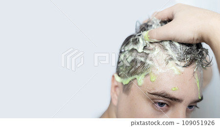 Man does head scrub. Dark-haired young man applies a scalp scrub to combat dandruff, oily scalp, alopecia. Problem skin causing hair problems. Close-up of self-massage and rubbing product into hair. Man does head scrub. Dark-haired young man applies a scalp scrub to combat dandruff, oily scalp, alopecia. Problem skin causing hair problems. Close-up of self-massage and rubbing product into hair. 109051926
