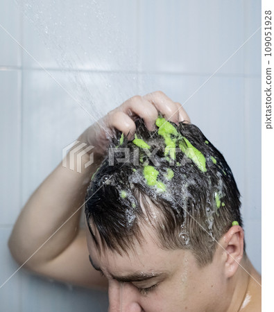 Man does head scrub. Dark-haired young man applies a scalp scrub to combat dandruff, oily scalp, alopecia. Problem skin causing hair problems. Close-up of self-massage and rubbing product into hair. 109051928