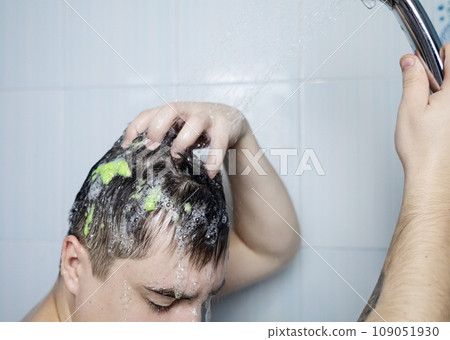 Man does head scrub. Dark-haired young man applies a scalp scrub to combat dandruff, oily scalp, alopecia. Problem skin causing hair problems. Close-up of self-massage and rubbing product into hair. 109051930