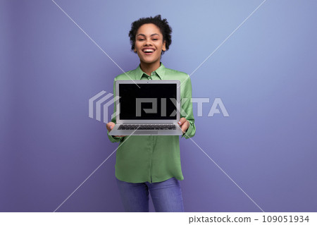 young cheerful positive hispanic brunette lady dressed in a green stylish blouse holds a laptop with 109051934