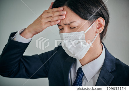 A young male office worker who has a headache and puts his hand on his forehead 109053154