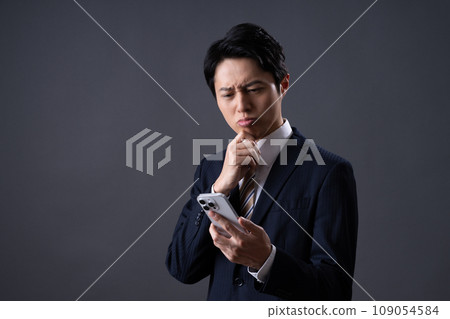 Middle-aged businessman looking at smartphone Middle-aged businessman looking at smartphone 109054584
