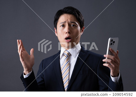 Middle-aged businessman looking at smartphone Middle-aged businessman looking at smartphone 109054592