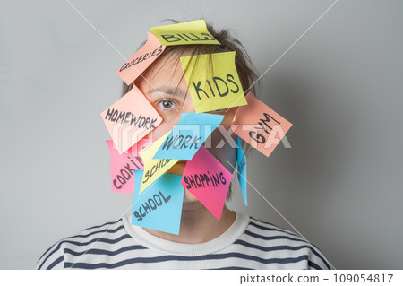 Mental load concept - female has post-it notes with social responcibilities on her face Mental load concept - female has post-it notes with social responcibilities on her face 109054817