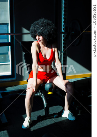 Girl athlete with black curly hair in bright sunlight in the gym 109056651