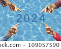2024, People pointing to the number 2024 on background of faded lights. Happy New Year 109057590