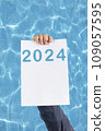 2024, Man holding cardboard with number 2024 on background of faded lights. Happy New Year 109057595
