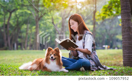 Young woman reading a book with her dog in the park AI-generated image 109057952