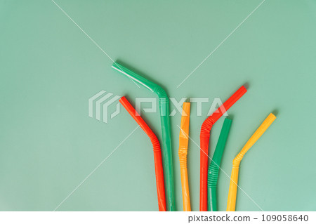Crumpled plastic straws of different colors on a green background Crumpled plastic straws of different colors on a green background 109058640