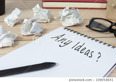 Any ideas question written on notepad with trash paper background on office desk 109058641