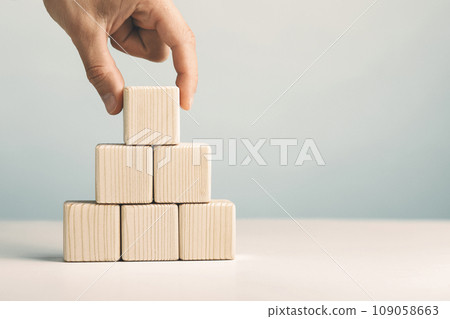 Hand putting and stacking blank wooden cubes on table with copy space for input wording or infographic icon Hand putting and stacking blank wooden cubes on table with copy space for input wording or infographic icon 109058663