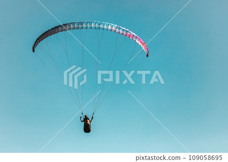 Paraglider in the sky. The sportsman flying on a paraglider. Paraglider in the sky. The sportsman flying on a paraglider. 109058695