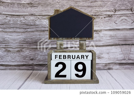 Chalkboard with date on white cube block on wooden table. 109059026