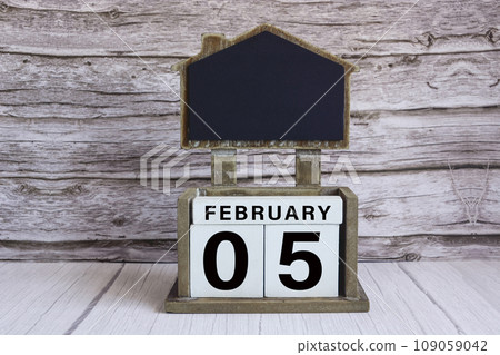 Chalkboard with date on white cube block on wooden table. 109059042