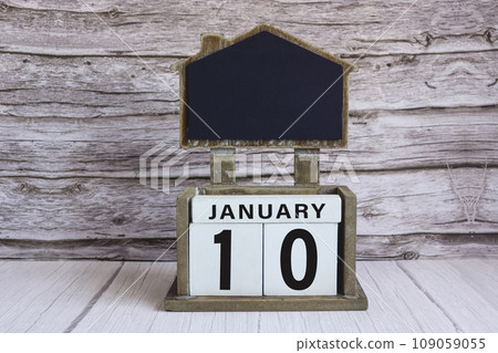 Chalkboard with January 10 date on white cube block on wooden table. 109059055