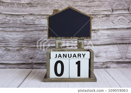 Chalkboard with January 01 date on white cube block on wooden table. 109059063