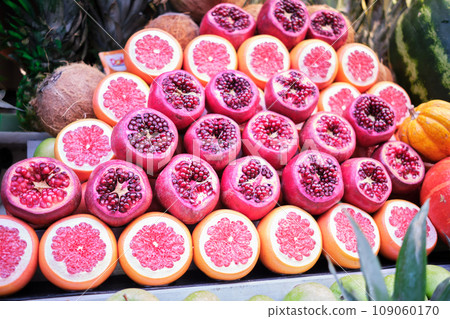 Sliced halves of pomegranate and grapefruit are on the counter of the store Sliced halves of pomegranate and grapefruit are on the counter of the store 109060170