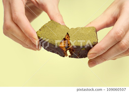 Woman's hands breaking vegan chocolate bar with dried fruits 109060507
