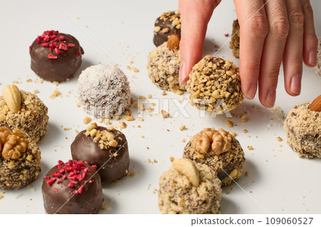 Woman taking chocolate candy from white table 109060527