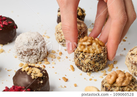 Woman taking chocolate candy from white table 109060528