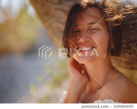 Beautiful Asian young woman in white dress outdoor near olive tree. embracing fresh air and engaging in outdoor activities. Friluftsliv concept means spending as much time outdoors as possible Beautiful Asian young woman in white dress outdoor near olive tree. embracing fresh air and engaging in outdoor activities. Friluftsliv concept means spending as much time outdoors as possible 109060695