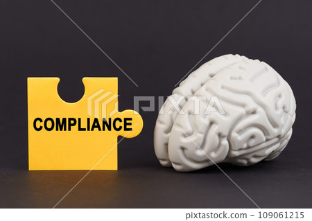 On a black surface there is a brain and a yellow puzzle with the inscription - COMPLIANCE On a black surface there is a brain and a yellow puzzle with the inscription - COMPLIANCE 109061215