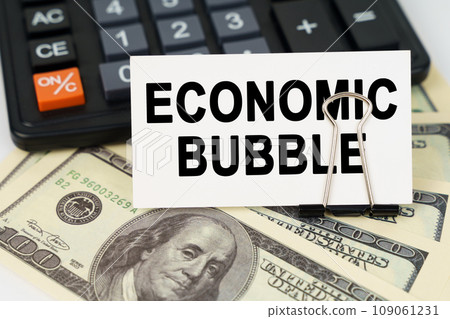 On the dollars there is a calculator and a business card with the inscription - ECONOMIC BUBBLE 109061231