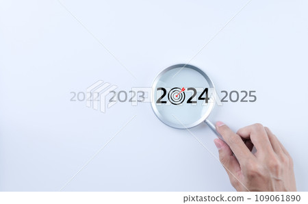 The 2024 new year business goals concept. A person holding a magnifying glass looking at the word year 2024 on white background. Business plan target strategy, Marketing trend 2024, Work focus, 109061890